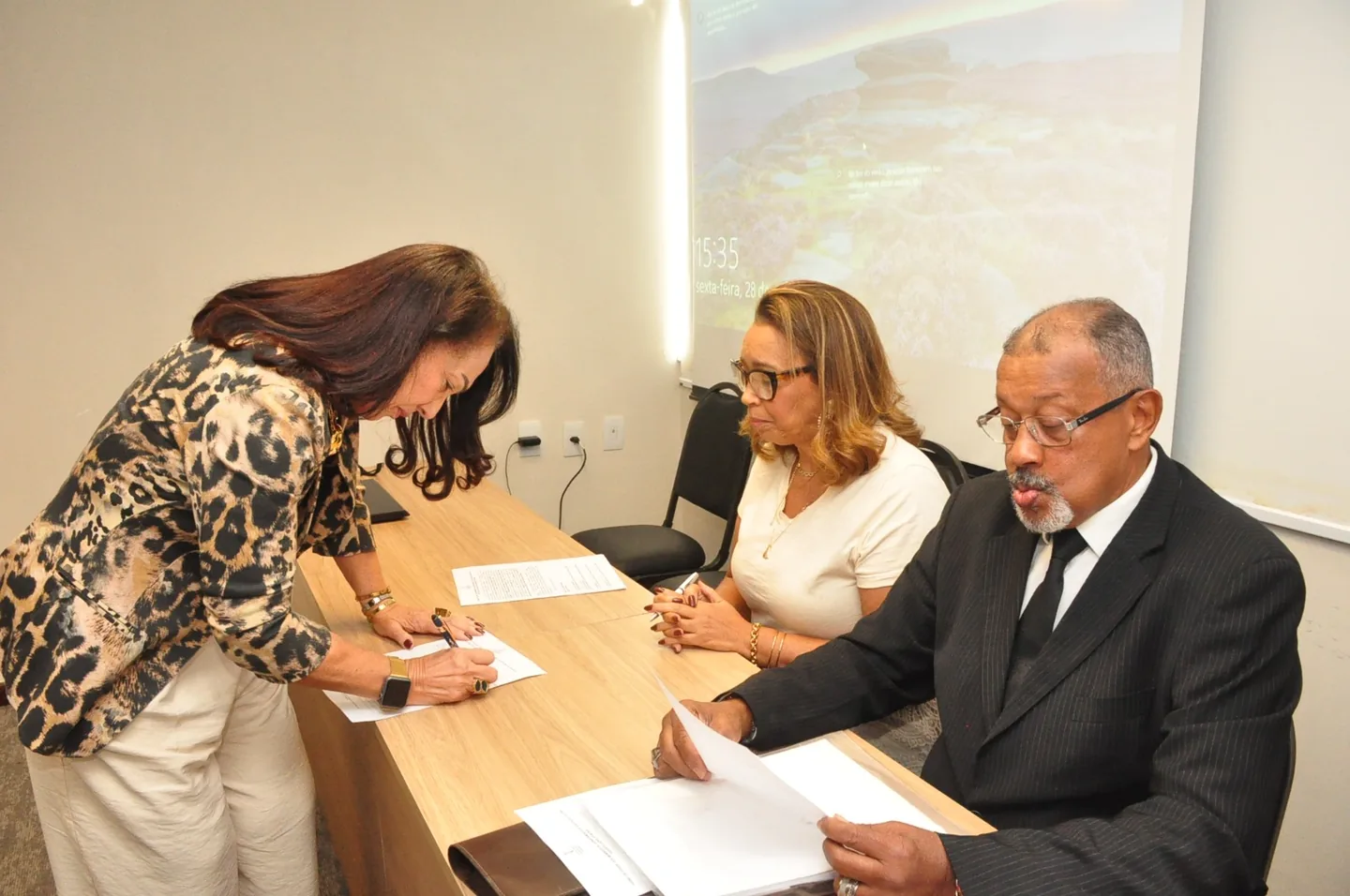 Integrante assina documento durante a solenidade de posse
